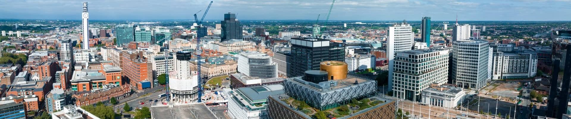 An aerial shot of Birmingham's skyline with cranes in the background.
